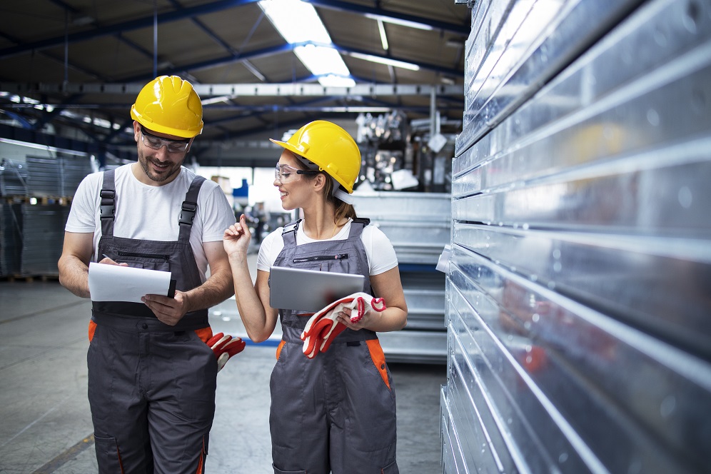 Factory workers working together in industrial production hall.