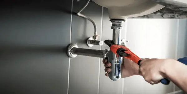 plumber-uses-wrench-repair-water-600nw-2466456607